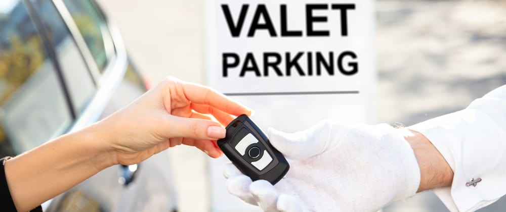Person handing over car keys to valet attendant